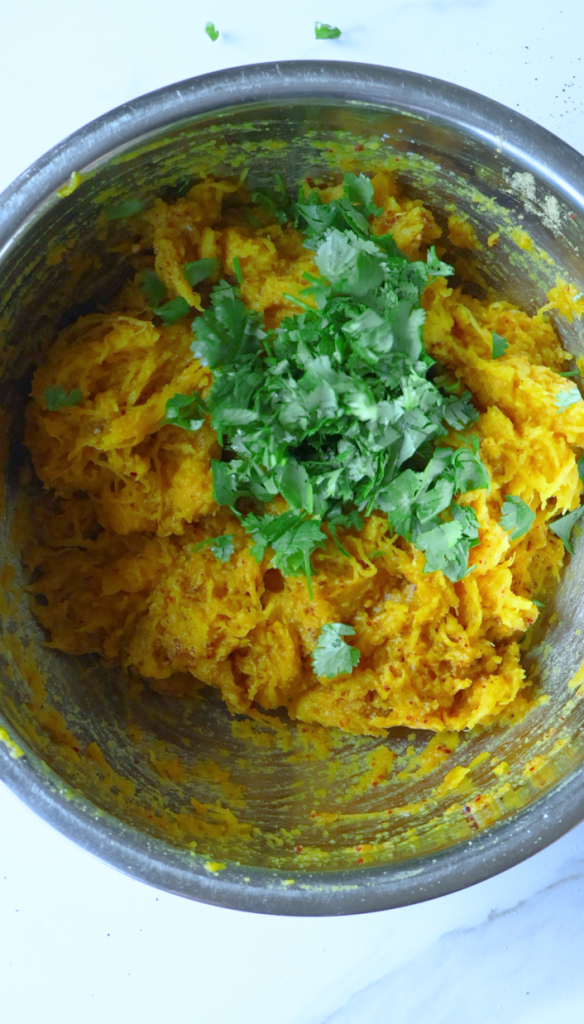 Remove the skin from your baked pumpkin, then mash pumpkin with chopped cilantro, black pepper, red chili flakes, coriander, garlic powder and salt.